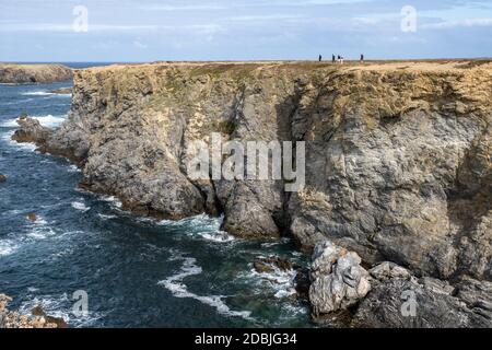 Personnes marchant le long des falaises aux Aiguilles de Port Coton, sur l'île de Belle Ile, Bretagne, France Banque D'Images
