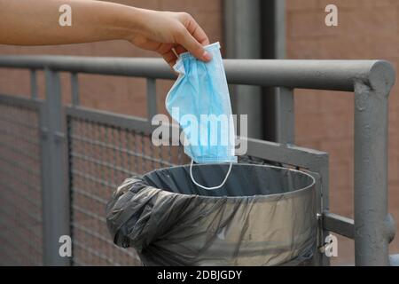 Jetez le masque chirurgical dans la poubelle publique de la rue. Le masque hygiénique se met dans les poubelles. Banque D'Images