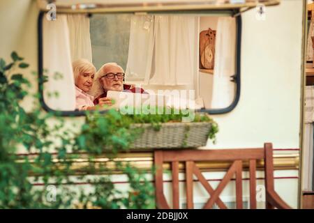 Couple senior regardant attentivement le nouvel itinéraire sur la carte tout en se relaxant dans leur camionnette de camping. Concept de voyage Banque D'Images