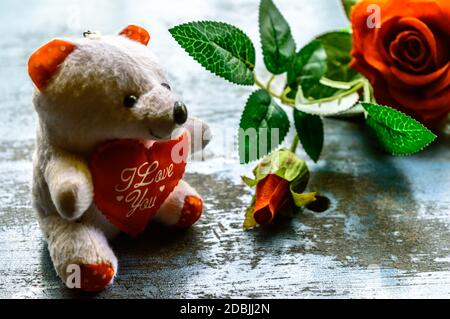 Je vous aime encore la vie romantique thème fond concept pour la Saint Valentin ou l'amitié. Fleur de rose rouge et ours en peluche sur un sol rustique. Papier peint W Banque D'Images