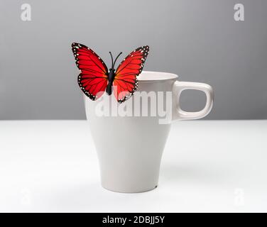 un faux papillon sur une tasse blanche Banque D'Images