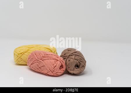 Trois balles de fil de laine coloré sur un fond blanc Uni avec espace de copie. Banque D'Images