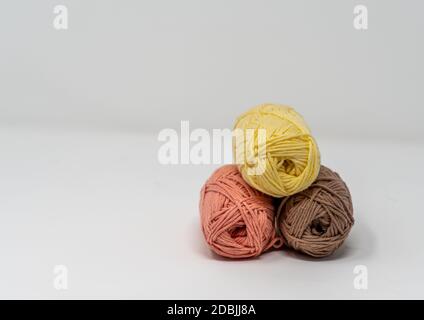 Trois balles de fil de laine coloré sur un fond blanc Uni avec espace de copie. Banque D'Images