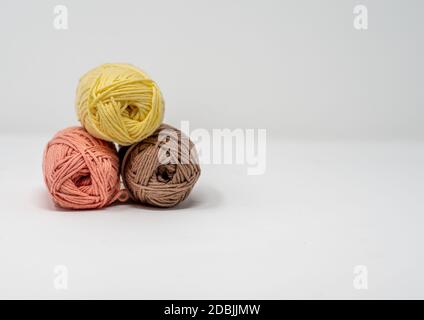 Trois balles de fil de laine coloré sur un fond blanc Uni avec espace de copie. Banque D'Images