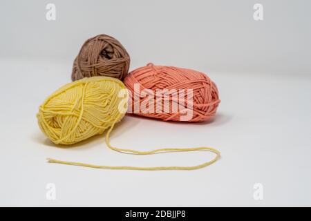 Trois balles de fil de laine coloré sur un fond blanc Uni avec espace de copie. Banque D'Images