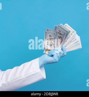 médecin dans un manteau blanc, portant des gants stériles bleus, le médecin tient un paquet d'argent papier, concept anti-corruption, pot-de-vin et le paiement pour le travail faire Banque D'Images