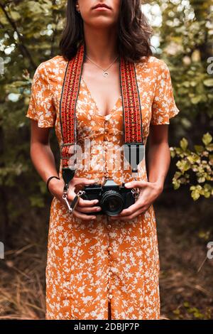 La photographe de fille dans les bois tient dans sa main un ancien appareil photo de film d'époque Banque D'Images