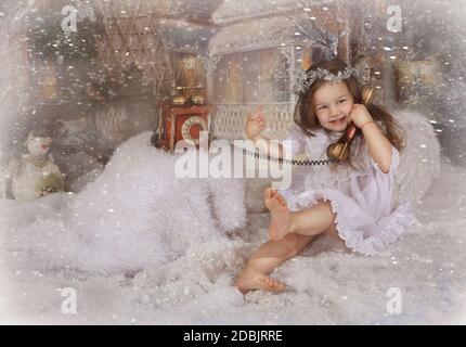 Belle petite fille habillée comme un ange dans les décorations de Noël Banque D'Images