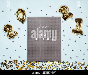 Tableau de lettres avec 2021 ballons et texte s'il vous plaît être bon sur le fond bleu avec des étoiles noires et or et des confetti de cercle. Noël ou nouvel an fe Banque D'Images
