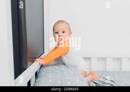 Un petit enfant en pyjama se trouve sur le lit et les langouls, se préparant pour le sommeil Banque D'Images