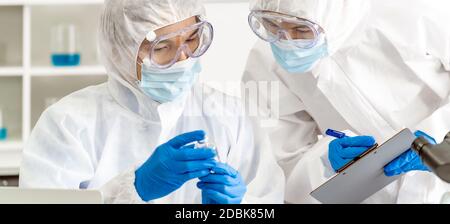 Un scientifique panoramique examine les tests de vaccination contre la pandémie de covid-19 du coronavirus en laboratoire scientifique. Les scientifiques portent des vêtements de protection individuelle EPI et des vêtements médicaux Banque D'Images