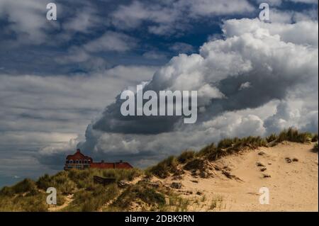 Vu des dunes en ruines, un immense nuage semble sortir d'un bâtiment. Banque D'Images