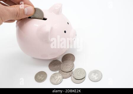 La main met le billet de banque dans la banque de piggy dans la forme de un porc isolé sur blanc Banque D'Images