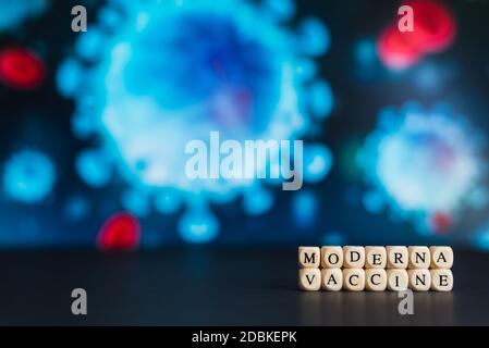 Image couleur horizontale avec une vue de face du nom de la société pharmaceutique moderna écrit avec des lettres en bois sur fond avec un certain coronavirus Banque D'Images
