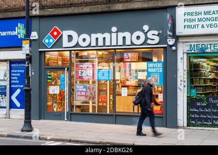 Un homme passe devant Domino's Pizza, ouvert à emporter lors du second confinement en cas de pandémie du coronavirus, à Kentish Town, Londres, Royaume-Uni Banque D'Images