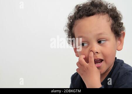 garçon cueillant son nez avec fond blanc photo Banque D'Images