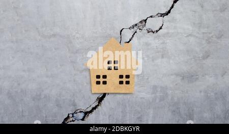Maison miniature sur fond de texture de mur de ciment fissuré. Vue de dessus Banque D'Images