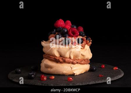 Luxueux dessert Pavlova avec baies fraîches et framboises sur fond sombre. Gâteau culinaire manger. Banque D'Images