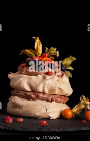 Pavlova dessert de meringue avec mélange de fruits sur fond sombre. Dessert de fête. Banque D'Images