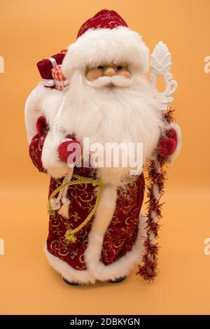 Statuette en céramique du Père Noël dans une tenue de manteau rouge personnel isolé sur fond jaune Banque D'Images