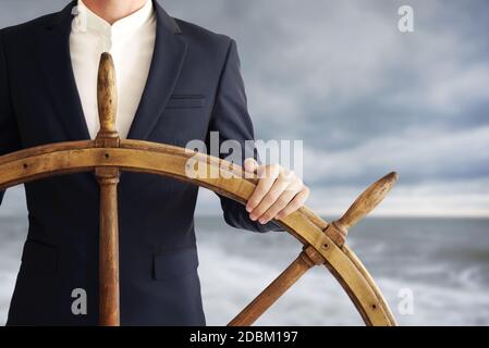 Homme d'affaires tenant le volant de navire et navigue dans la tempête. Banque D'Images