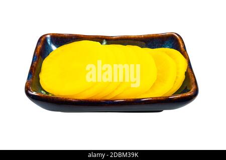 Plat d'accompagnement traditionnel coréen et japonais Takuan (Danmuji) du radis daikon mariné dans un bol en céramique isolé sur fond blanc Banque D'Images