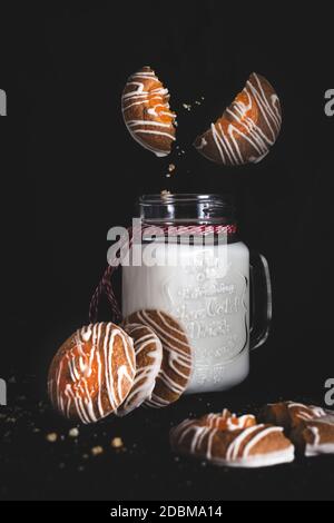 Les biscuits cassés et les miettes tombent dans un verre de lait décoré d'un ruban de Noël. Cookies sur la table. Mise au point sélective. Banque D'Images