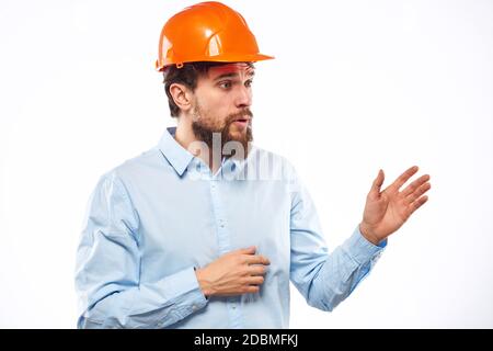 Un homme dans une industrie de construction de chemise de casque orange a travaillé arrière-plan clair Banque D'Images