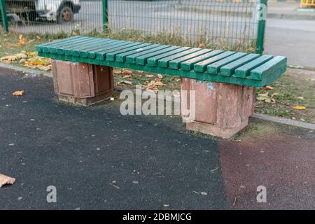 Banc en bois vert sur le revêtement en caoutchouc de l'aire de jeux Banque D'Images