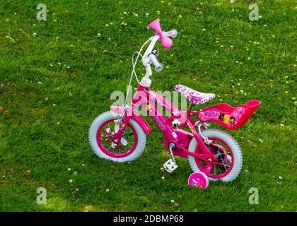 vélo à pédales rose de 12 pouces pour fille avec roues d'entraînement ombre ouverte sur la cour de la prairie verte Banque D'Images