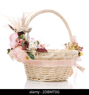 Panier de Pâques sur fond blanc. Décoré de fleurs roses et d'un petit lièvre en céramique décoratif. Rubans et dentelle. Vue latérale. Banque D'Images