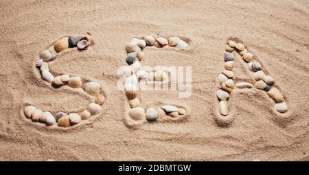 Une plage avec une inscription en anglais: mer. Les lettres sont faites par des coquillages. Vacances en mer. Banque D'Images