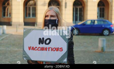 Jeune femme protestant contre la vaccination. Elle a porté un masque de protection et elle a marché dans la rue Banque D'Images