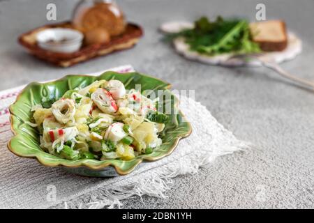 Sur la table dans une assiette de céramique salade de légumes de chou, poivre, oignons verts, bâtonnets de crabe. À côté des épices et du pain Banque D'Images