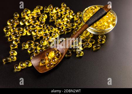 Capsules de gel oméga 3 d'huile de foie de morue sur fond noir. La vitamine D et les oméga-3 dorés pilules pour une alimentation saine. Prévention de la grippe. Banque D'Images