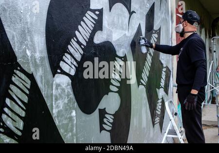 Graffiti artiste en action, debout sur des échelles et portant masque de protection / respirateur avec filtres. Dessin abstrait avec peinture en aérosol dans une bombe. Banque D'Images