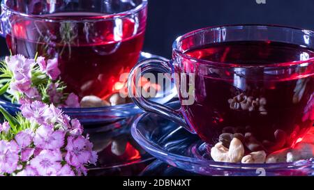 Hibiscus thé rouge mug avec carnation fleurs gros plan horizontal photo.tradition du thé anglais.thérapie médicinale à base d'herbes médicinales et de décoctions. Banque D'Images