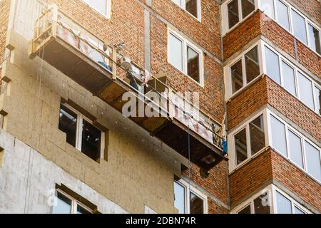 Travail à haute altitude sur les murs extérieurs de l'isolation en laine de verre et de plâtre Banque D'Images