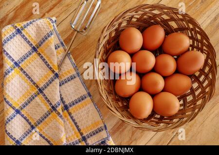 Vue de dessus des œufs bruns dans un panier en osier. Œufs dans un panier en bois sur une table en bois. Banque D'Images