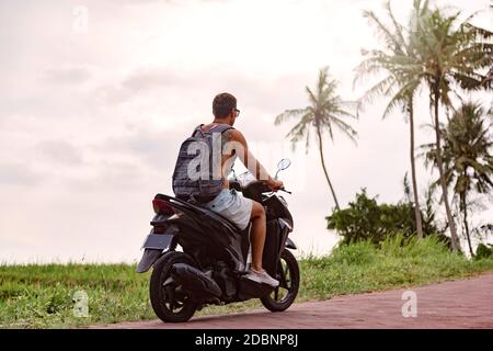 Homme conduisant une moto sur la route, Bali, Indonésie Banque D'Images