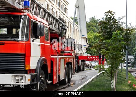 De nombreux chariots à moteur d'incendie avec échelle et équipement de sécurité à accident dans un immeuble résidentiel ou de bureau de tour haute à centre ville Banque D'Images