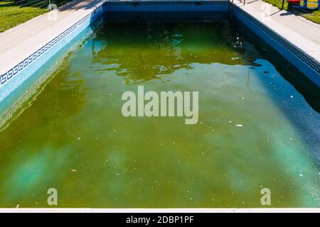 Piscine abandonnée avec eau pourrie verte à l'extérieur. Banque D'Images