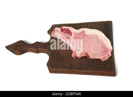 une viande de porc crue sur un os repose sur une planche à découper brune, la nourriture est isolée sur un fond blanc, vue de dessus Banque D'Images