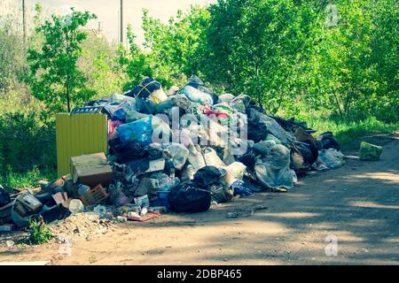 Décharge illégale près de la route de sable de pays dans le pays le jour de soleil. Corbeille de la pollution dans la nature. Dirty dépotoir près de bois de la forêt. Vert tonique Banque D'Images