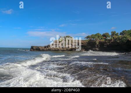 Côte de l'océan Indien près du temple sacré balinais Tanah Lot. Pura Batu Bolong au bord d'une falaise au bord de la côte avec trou dans la roche. Lieu Saint f Banque D'Images