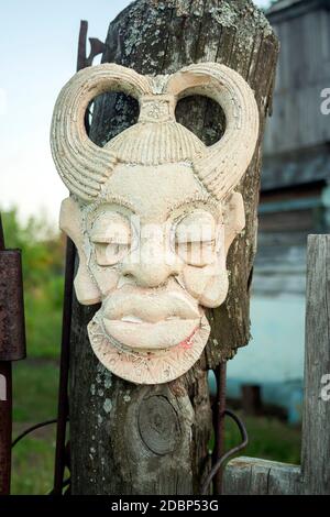 Ancien masque africain ancien fait main sur clôture en bois près de la maison. La culture africaine masques traditionnels close up Banque D'Images