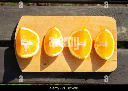 appétissant morceaux de fruits oranges coupés sur planche à découper sur table en bois brun sur les lampes solaires. saine alimentation, fruits, vue de dessus d'été Banque D'Images