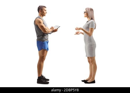 Photo pleine longueur d'une jeune femme qui parle un instructeur de fitness isolé sur fond blanc Banque D'Images