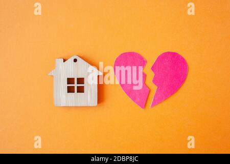 Divorce, division de la propriété, pauvreté et aucun concept d'argent. Maison en bois avec coeur cassé sur fond orange vif. Hypothèque, loyer, réalteur Banque D'Images