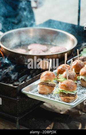 Chef cuisant des hamburgers de bœuf à l'extérieur lors d'un festival de cuisine ouverte. Cuisine de rue prête à servir dans un restaurant. Banque D'Images